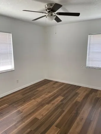 an empty room with wooden floor closet and windows