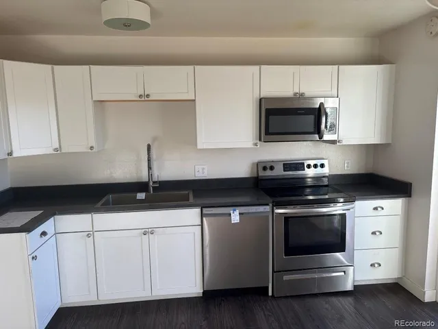 a kitchen with white cabinets and appliances