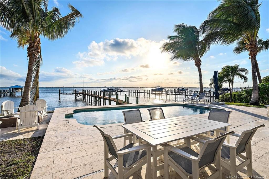 4230 Northeast Joes Point Road Jensen Beach, FL 34957 - Photo 14 of 62 a roof deck with a table and chairs under an umbrella