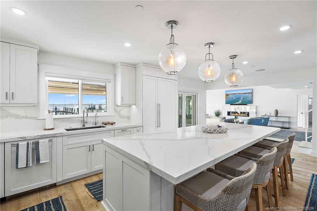 4230 Northeast Joes Point Road Jensen Beach, FL 34957 - Photo 25 of 62 a kitchen with a stove a sink dishwasher a dining table and chairs with wooden floor