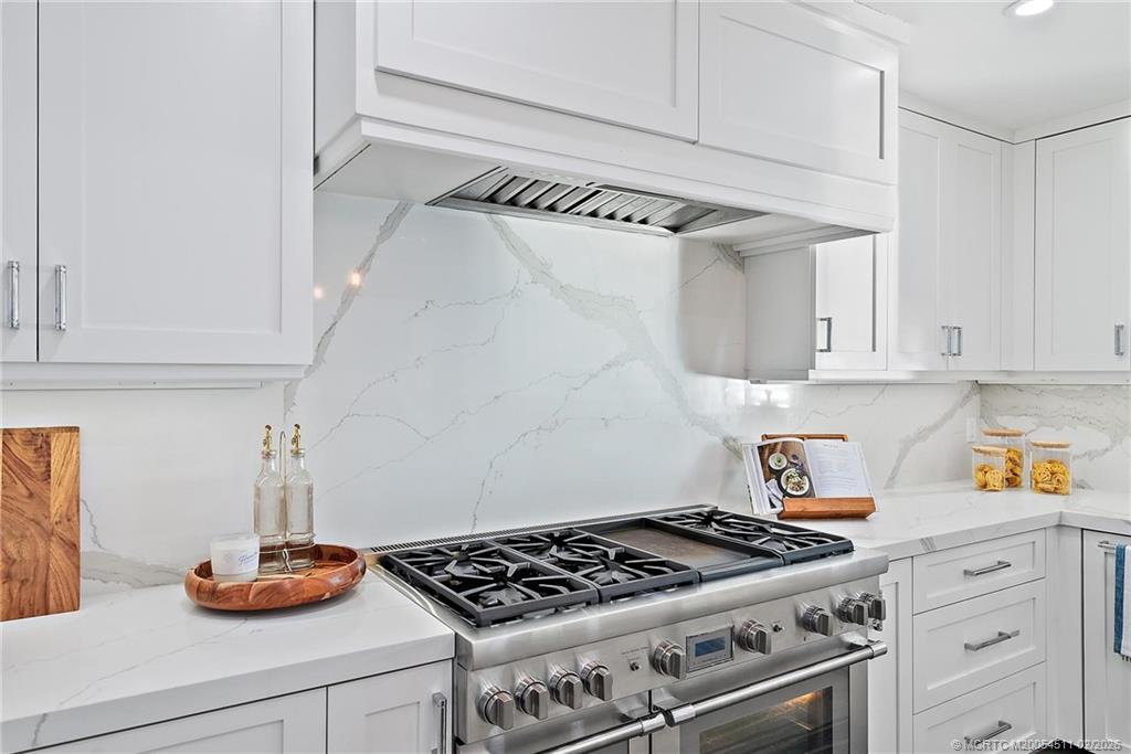 4230 Northeast Joes Point Road Jensen Beach, FL 34957 - Photo 29 of 62 a kitchen with white cabinets and a stove with wooden floor