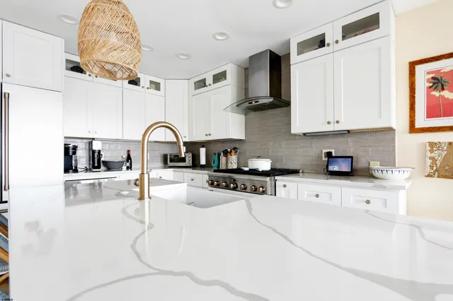 a kitchen with stainless steel appliances granite countertop a sink a stove and white cabinets with wooden floor