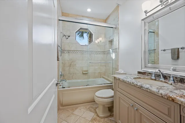 a bathroom with a granite countertop bathtub toilet sink and mirror
