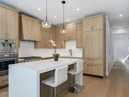 a kitchen with stainless steel appliances granite countertop a sink a stove a refrigerator and island with wooden floor