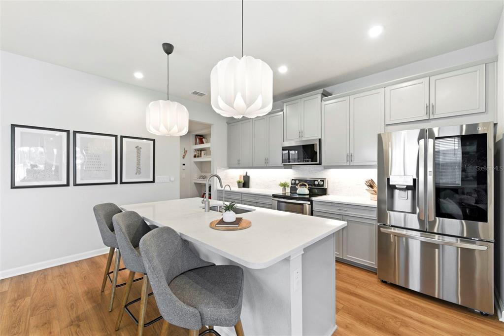 4327 Cloud Hopper Way Lutz, FL 33559 - Photo 13 of 75 a kitchen with stainless steel appliances granite countertop a dining table chairs refrigerator and microwave