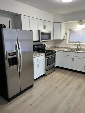 a kitchen with stainless steel appliances granite countertop a refrigerator a stove top oven a sink and dishwasher