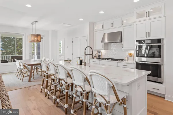 a kitchen with stainless steel appliances granite countertop a stove top oven a sink a refrigerator and white cabinets