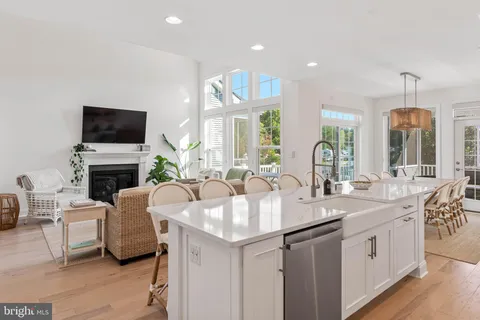 a large white kitchen with a sink and a fireplace