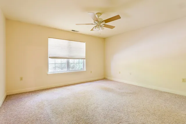 an empty room with a window and a fan