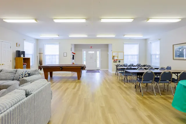 a living room with furniture pool table wooden floor and windows