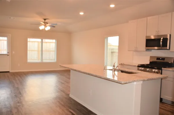 a kitchen with granite countertop a stove a sink and a microwave