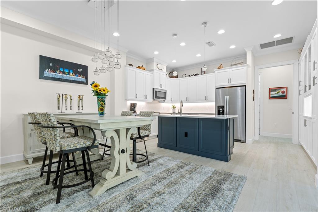 8781 Yucatan Court Naples, FL 34113 - Photo 11 of 36 a kitchen with stainless steel appliances kitchen island granite countertop a table chairs sink and wooden cabinets