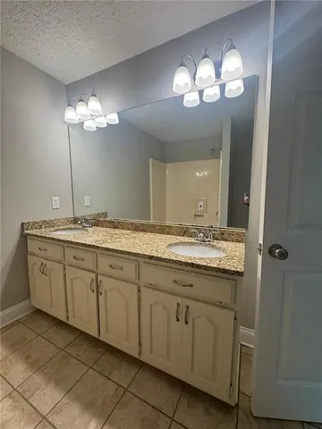 a bathroom with a granite countertop sink a light fixture and a mirror