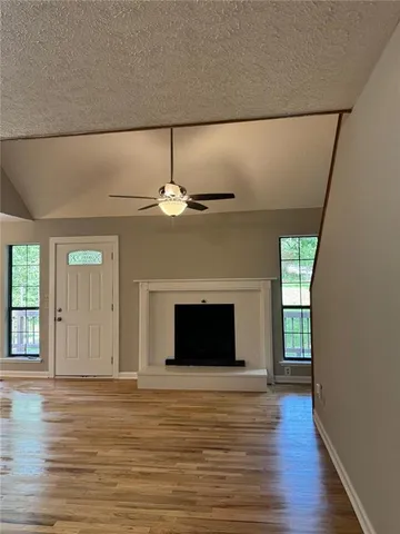 an empty room with wooden floor fireplace and chandelier