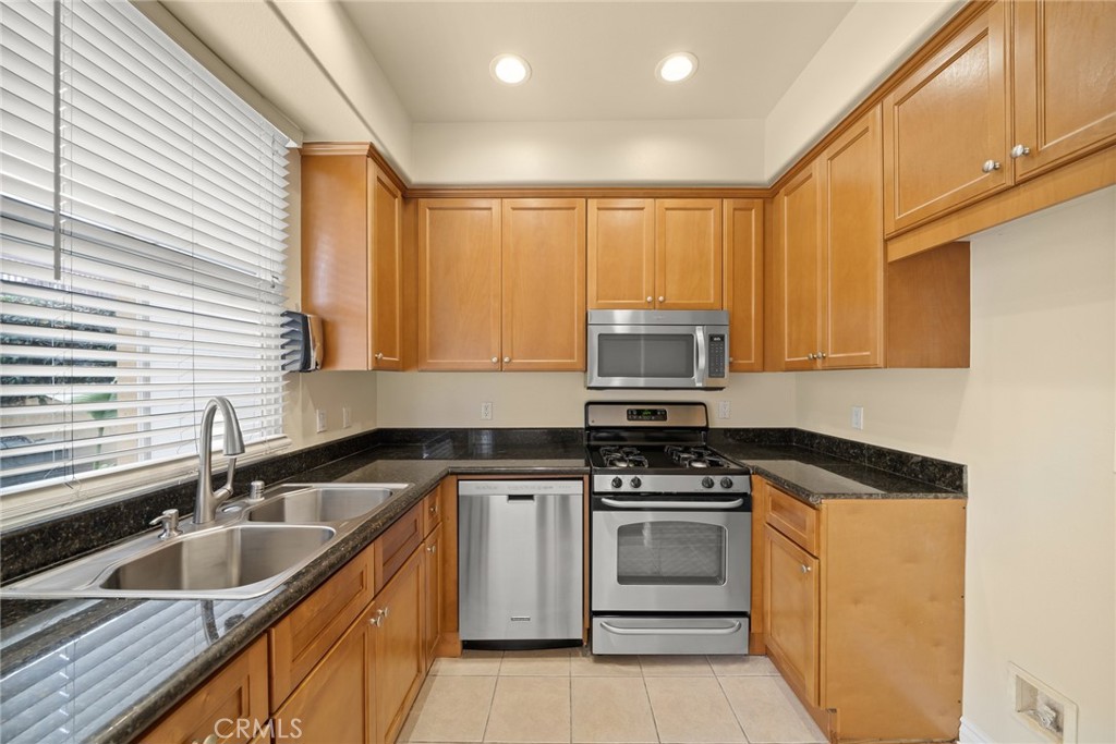 1500 Pine Avenue, Unit 9 Long Beach, CA 90813 - Photo 5 of 30 a kitchen with granite countertop a sink stainless steel appliances wooden cabinets and a window