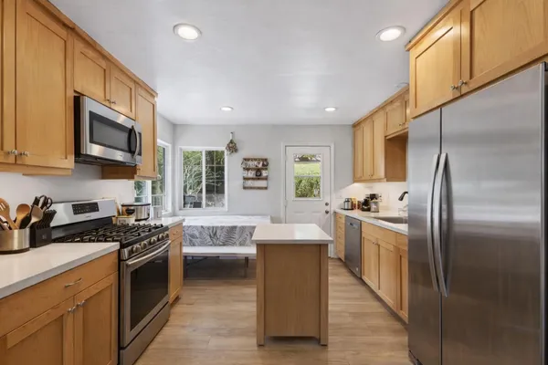 a kitchen with stainless steel appliances granite countertop a stove a sink dishwasher a refrigerator and a microwave