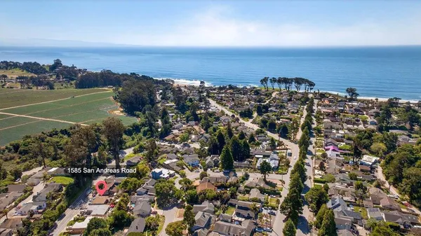 an aerial view of a city with lots of residential buildings and ocean view in back