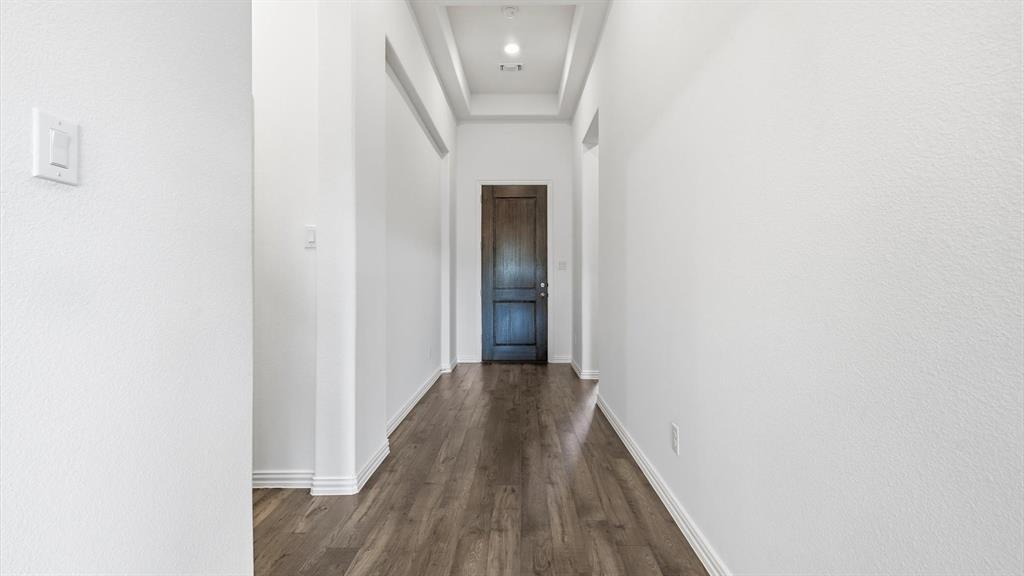 2529 Rivers W Road Anna, TX 75409 - Photo 8 of 40 Hallway featuring wood-finish flooring, white baseboards, recessed lighting, and a dark wood door