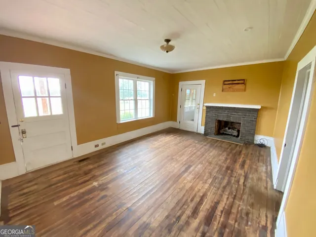 a view of an empty room with window wooden floor and front door