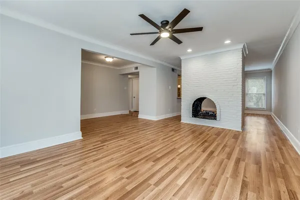 an empty room with wooden floor and a fireplace