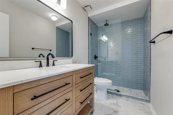 a bathroom with a sink a toilet a mirror and shower