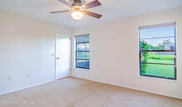 an empty room with a window and a fan