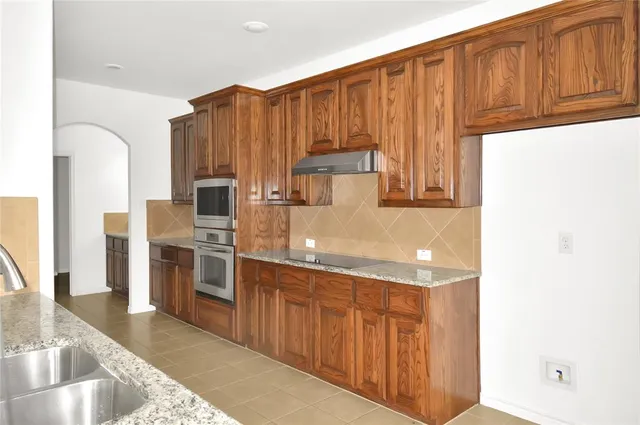 a kitchen with stainless steel appliances granite countertop a refrigerator and a stove top oven