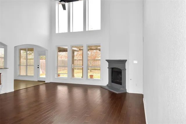 an empty room with wooden floor fireplace and windows