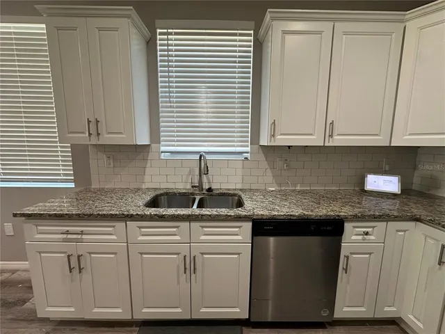 a kitchen with granite countertop white cabinets and a sink