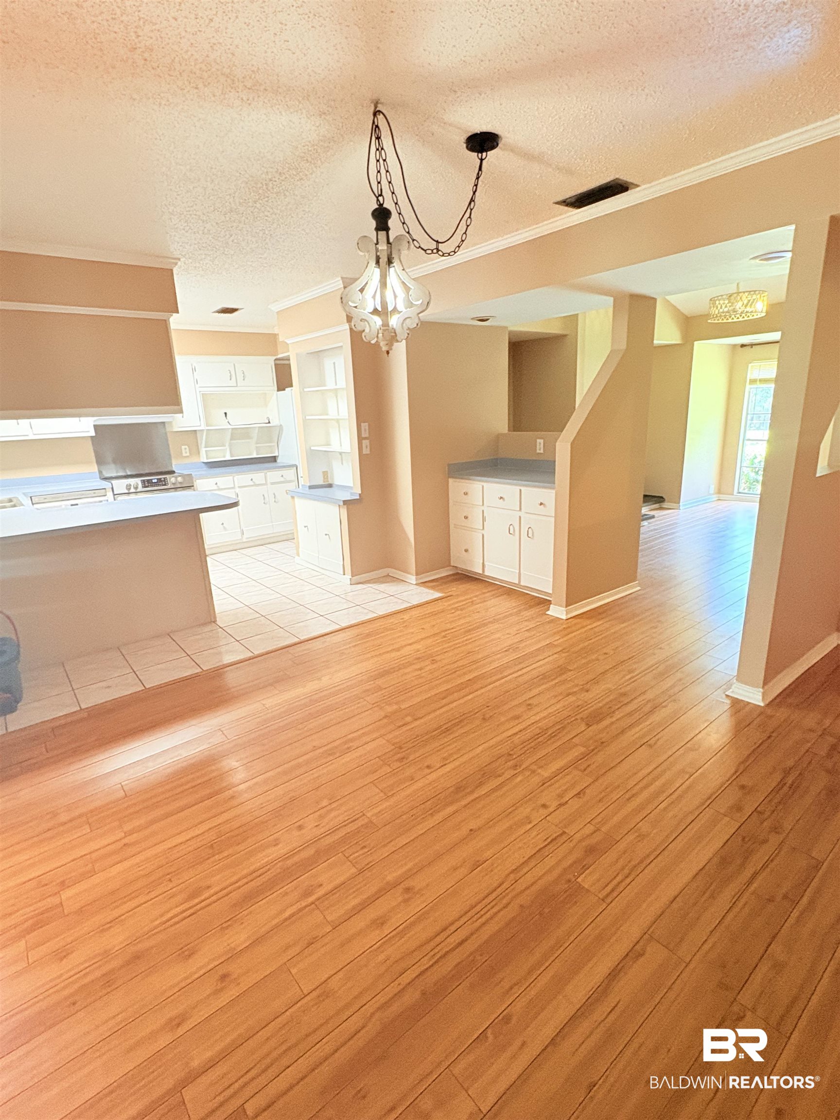 8070 Middle Ring Road Mobile, AL 36619 - Photo 4 of 26 Unfurnished living room featuring crown molding, a textured ceiling, a chandelier, and light wood finished floors