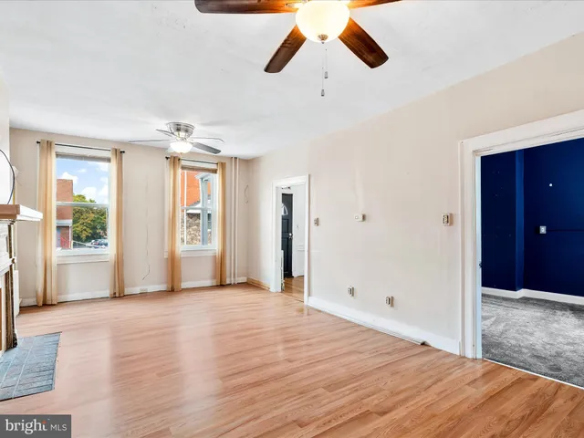 a view of an empty room with window and wooden floor