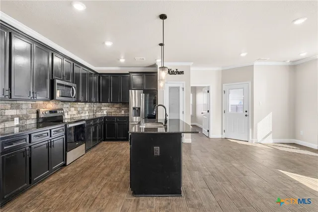 a kitchen with stainless steel appliances granite countertop a refrigerator a sink dishwasher a stove and white countertops with wooden floor