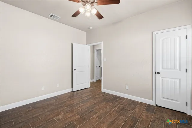 an empty room with wooden floor and ceiling fan