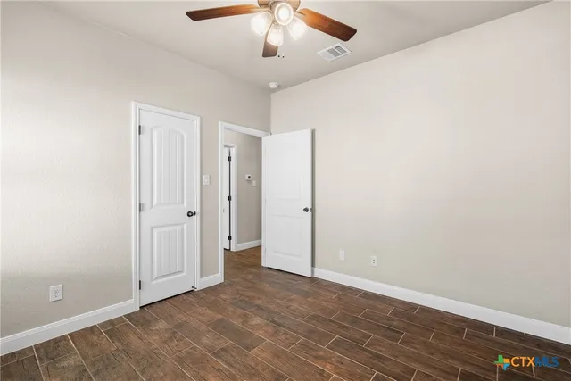 an empty room with wooden floor chandelier fan and closet area