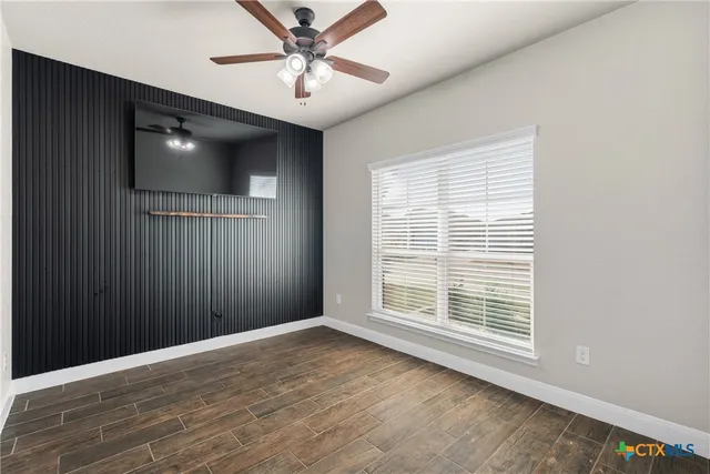 a view of an empty room with a window and wooden floor
