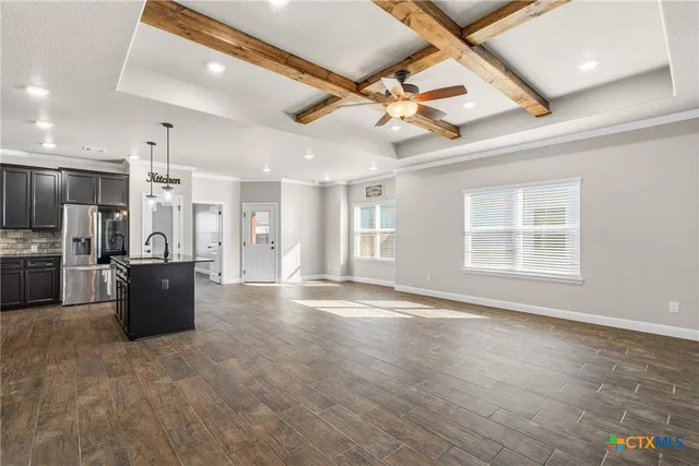 a view of an empty room with kitchen appliances and a ceiling fan