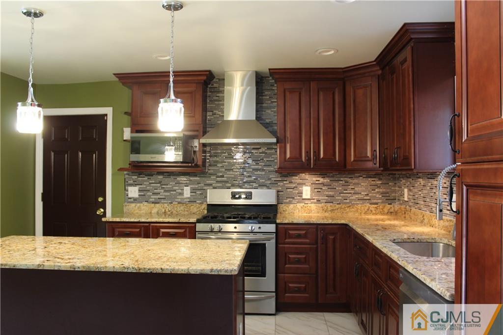 15 Kenmore Road Edison, NJ 08817 - Photo 8 of 35 a kitchen with kitchen island granite countertop a sink a counter space and cabinets