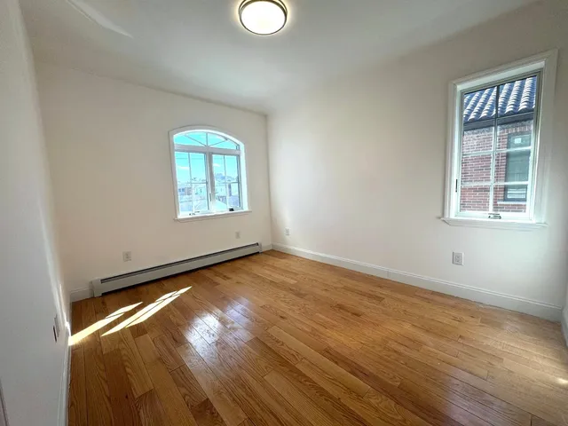an empty room with wooden floor cabinet and windows