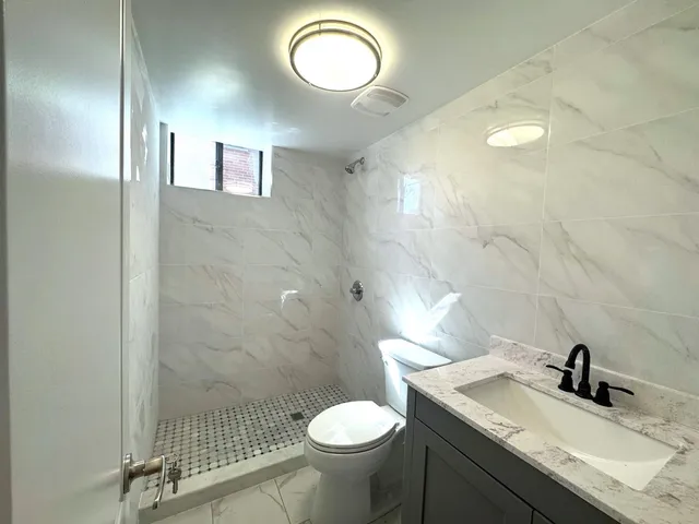 a bathroom with a granite countertop toilet sink and mirror