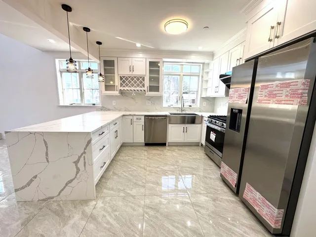 a large kitchen with stainless steel appliances granite countertop a sink stove and refrigerator