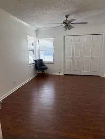 a view of empty room with wooden floor and fan