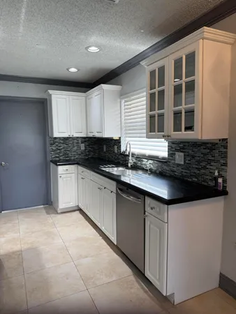 a kitchen with granite countertop a sink and white cabinets
