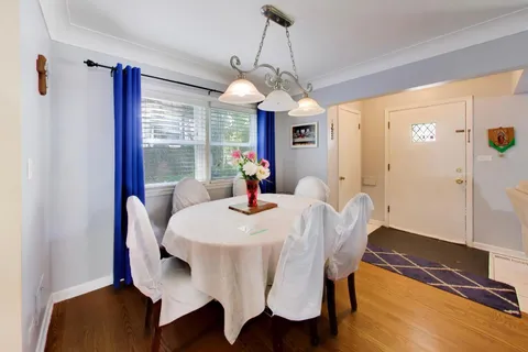 a dining room with wooden floor a chandelier a wooden table and chairs