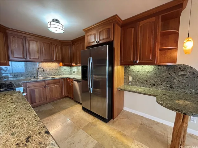 a kitchen with stainless steel appliances granite countertop a refrigerator a stove and a sink with wooden cabinets