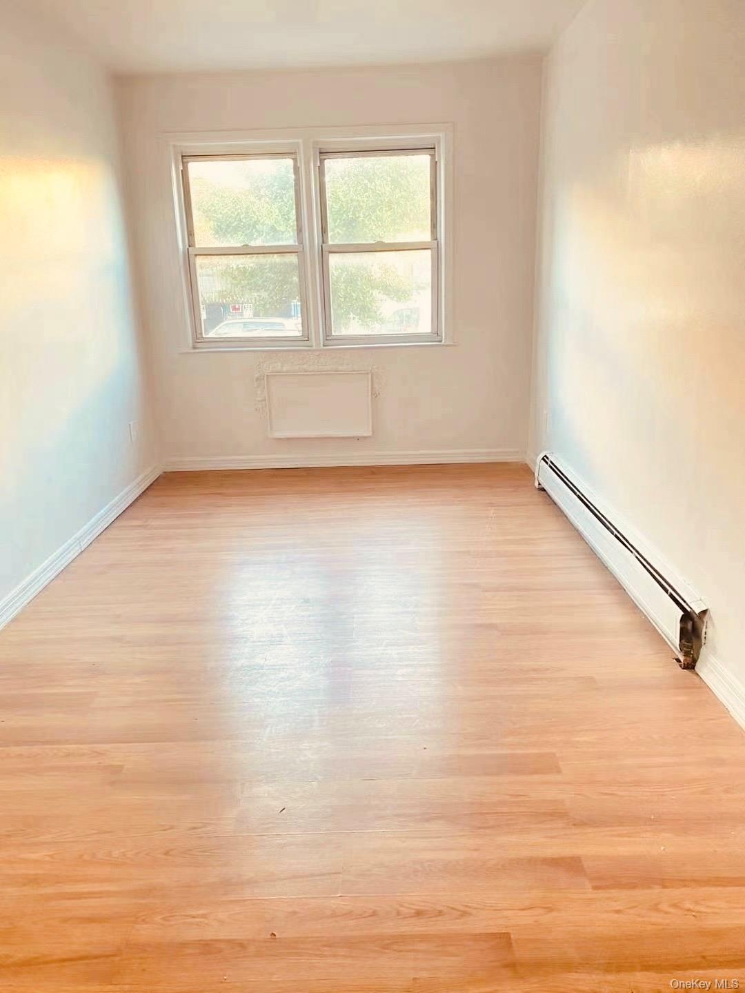 41-08 111th Street Queens, NY 11368 - Photo 3 of 9 an empty room with wooden floor and windows