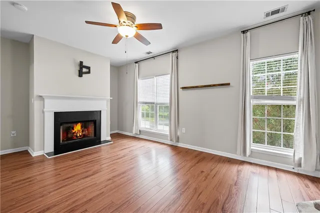 a view of an empty room with wooden floor fireplace and a window