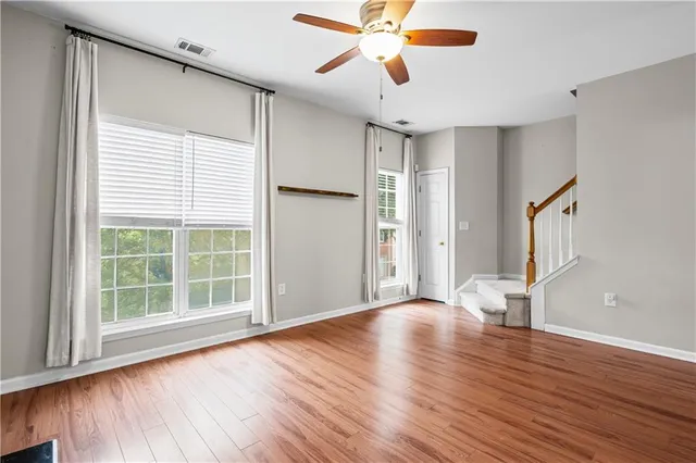 a view of an empty room with a window and wooden floor