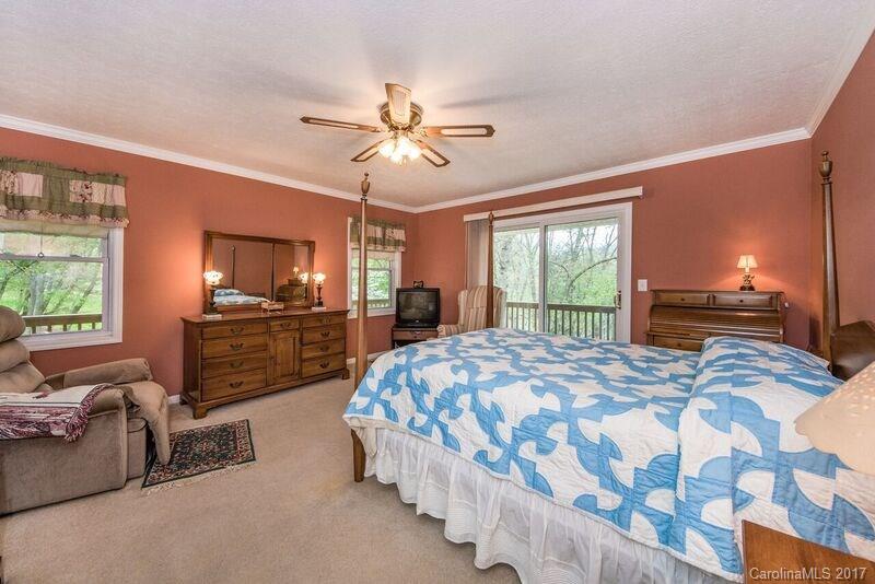 501 Oak Ridge Drive Clyde, NC 28721 - Photo 13 of 24 a spacious bedroom with a bed a dresser and a chandelier