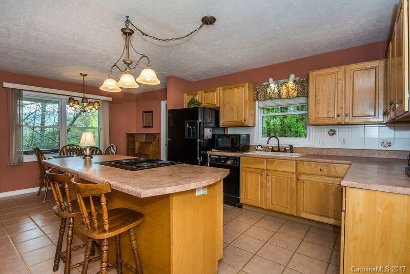 501 Oak Ridge Drive Clyde, NC 28721 - Photo 10 of 24 a kitchen with stainless steel appliances granite countertop a stove a refrigerator a sink dishwasher a dining table and chairs with wooden floor