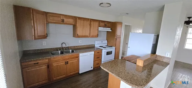 a kitchen with stainless steel appliances granite countertop a sink a stove and a refrigerator